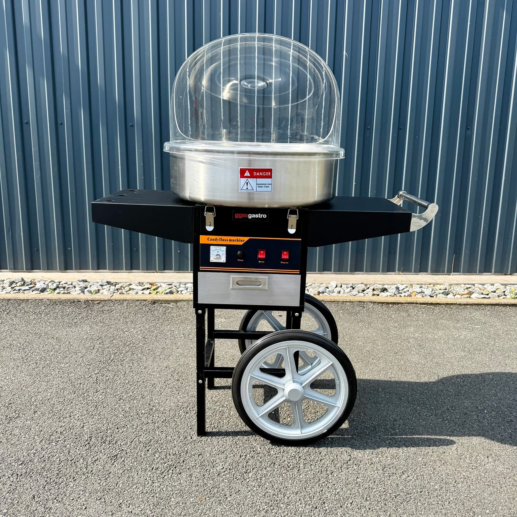 Zuckerwattemaschine mit transparenter Haube auf schwarzem Wagen